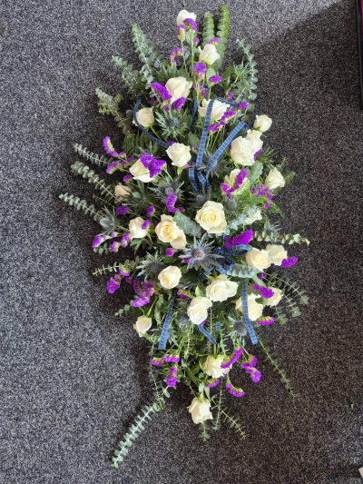 Scottish Remembrance Spray - A natural funeral spray in white and purple tones, finished with traditional tartan ribbon.